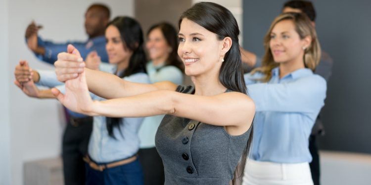 Kontorsanställda gör stretchövningar tillsammans under ett företagsevent.